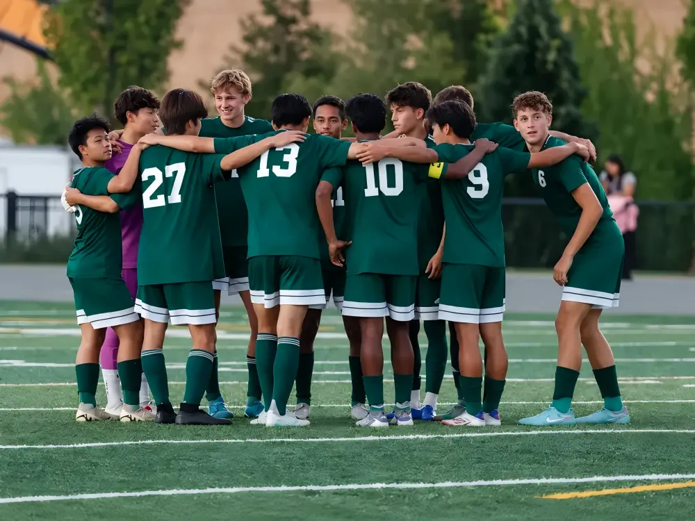 Youth soccer team wearing matching custom soccer jerseys during a team huddle on the field.