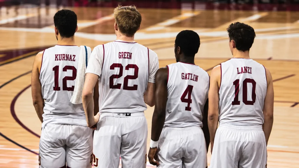 Four basketball players wearing white custom basketball jerseys featuring different player names and numbers on the back while standing on the court.