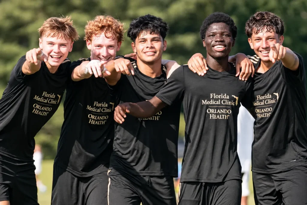 Five youth soccer players wearing matching black custom soccer jerseys and shorts, standing together and smiling on an outdoor soccer field.